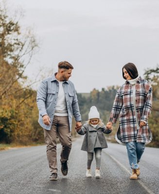 Family with little daughter together in autumnal weather having fun