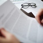 Image of business objects with businessman hand signing contract near by
