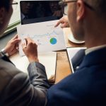 Business people analyzing visitors activity statistics, view over the shoulder